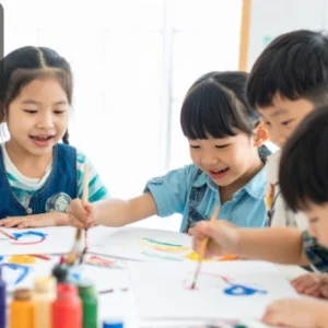 A group of young children happily painting together at a table with colourful paints and brushes.