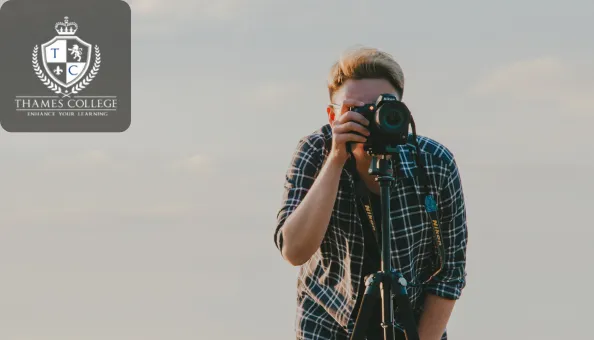 A photographer looking through a camera mounted on a tripod, preparing to capture a shot in natural light.