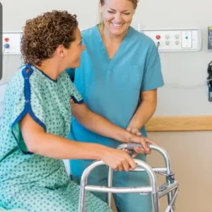 A healthcare assistant helping a patient with a walker in a hospital setting, providing care and encouragement.