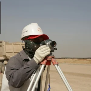 Surveyor wearing protective gear using equipment to inspect land for asbestos risks.