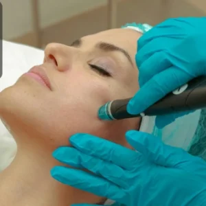 A beauty therapist wearing gloves performing a skin treatment on a client’s face in a salon setting.