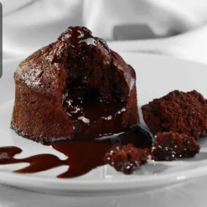 Delicious chocolate lava cake with a rich molten centre and sauce drizzled on a white plate, featuring the Thames College logo in the corner.