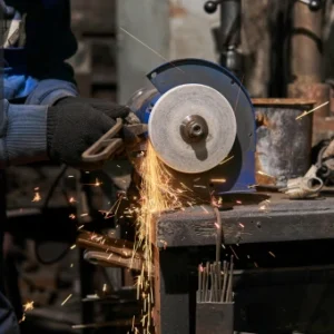 Worker using an abrasive wheel cutting machine, with sparks flying during the grinding process.