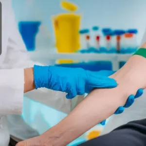 A healthcare professional wearing gloves prepares a patient’s arm with a tourniquet for blood collection in a clinical laboratory setting.