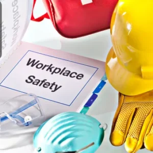 A workplace safety manual surrounded by PPE including a hard hat, gloves, safety goggles, and a face mask.