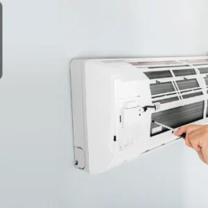 Smiling technician repairing a wall-mounted air conditioner, symbolising HVAC basics and professional skills.