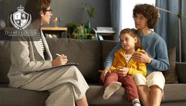 A family support worker speaks with a mother and child during a counselling session on a sofa, with the mother holding the child closely. The Thames College logo is displayed in the top-left corner.