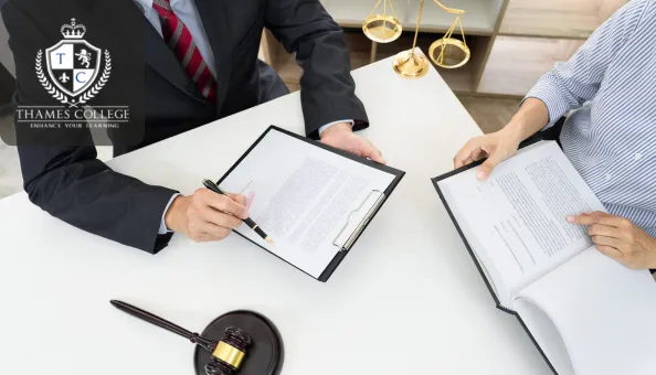 Two professionals review legal documents at a desk, with a gavel and scales of justice nearby. One person holds a pen and clipboard, while the other references a book. The Thames College logo is shown in the top-left corner.