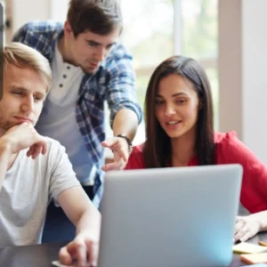 A group of beginners collaborating on a project using a laptop, symbolising teamwork and creativity in digital design.