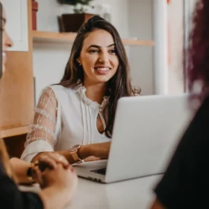Smiling marketing professional using a laptop while engaging with colleagues, representing Instagram marketing strategies.