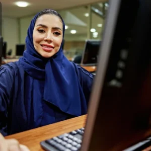 Confident woman in a computer lab smiling at the camera, symbolising learning Jira and Confluence for project management.
