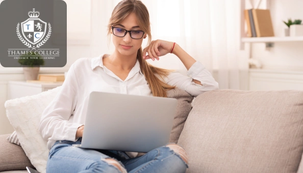 Young woman sitting comfortably on a sofa, working on her laptop, symbolising flexible online learning in Adobe Illustrator.