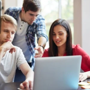 A group of three young professionals collaborating on a business project, symbolising teamwork and entrepreneurship.