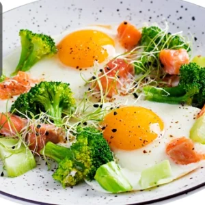 Plate of fried eggs served with broccoli, salmon pieces, and sprouts, representing a healthy ketogenic meal, with the Thames College logo in the corner.