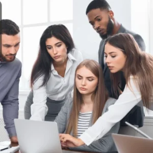 A group of professionals gathered around a laptop, engaged in a business meeting and brainstorming ideas.