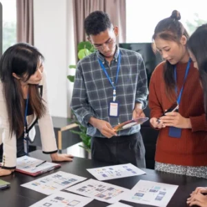 Team of professionals gathered around a table with branding materials, planning strategies for business identity and growth.