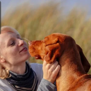 A woman gently interacting with her dog outdoors, showing affection and mutual trust, with the Thames College logo in the top-left corner.