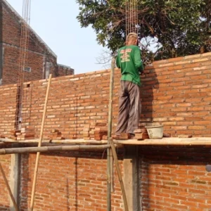 Workers building a brick wall on scaffolding as part of a construction project.