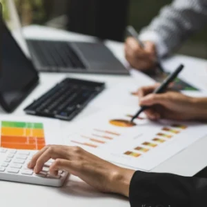 Professionals analysing financial reports with a calculator, charts, and laptops, symbolising financial planning and advisory skills.
