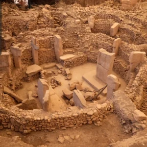 An ancient archaeological site with circular stone structures and large standing pillars.