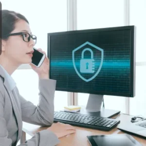 A professional in a suit talking on the phone while working on security management, with a digital lock symbol on the screen.