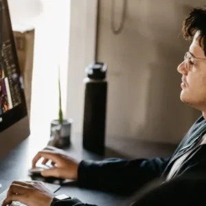 A graphic designer working on a computer, creating and arranging visual elements for a project with a focus on UX design principles.