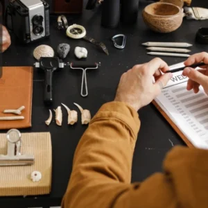 A researcher examining archaeological artefacts and fossils on a desk alongside geology tools and notebooks.