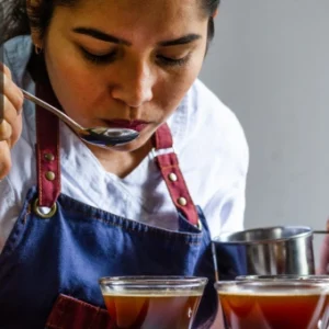 A barista carefully tasting brewed coffee to perfect flavour and quality during training.