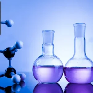Three laboratory glass flasks filled with purple liquid next to a molecular model on a reflective surface, with a blue-toned background.