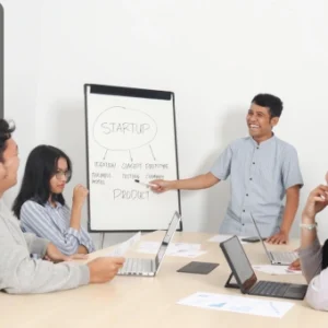 Young entrepreneur presenting a startup plan on a whiteboard to a small team in a meeting room, with laptops and documents on the table, and the Thames College logo in the corner.