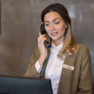 A concierge answering a phone call while standing behind a reception desk, providing customer service.