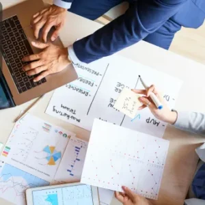 Professionals working with charts, reports, and a laptop, symbolising document control, organisation, and data management.