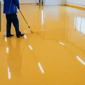 A professional applying a coat of floor coating, demonstrating skills learned in the Advanced Diploma in Cleaning Level 7.