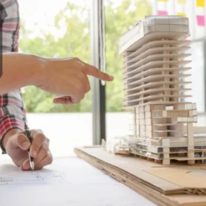 Architects reviewing building plans beside a detailed scale model of a modern high-rise structure.