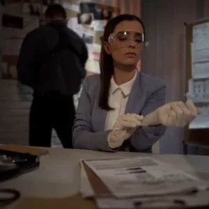 Female criminology student wearing safety goggles and gloves at a crime investigation desk, preparing for forensic analysis; male colleague reviewing evidence board in the background.
