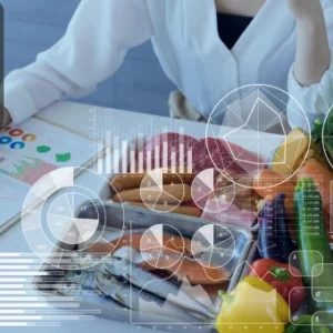 A nutritionist reviewing charts with fresh vegetables, fruits, fish, and meat on a table, symbolising animal nutrition planning.