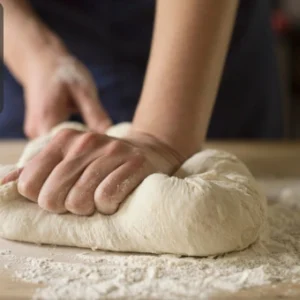 Close-up of hands kneading dough on a floured surface during bread making.