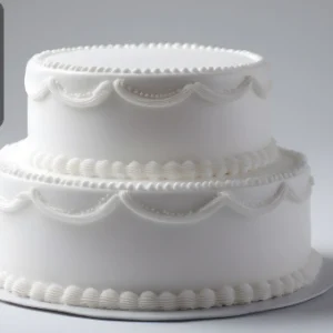 Elegant two-tier white cake decorated with smooth icing and delicate piped frosting details, with the Thames College logo in the corner.