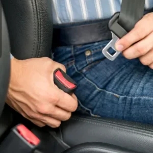 Close-up of a person fastening a seatbelt while seated in a vehicle.