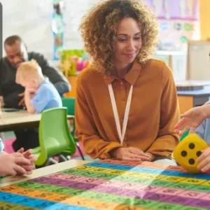 A teacher interacting with children in a classroom setting, using educational toys and tools, symbolising the Early Years Foundation Stage (EYFS) approach.