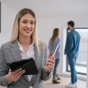 A smiling real estate agent holding a tablet and pen, with a couple viewing a property in the background.