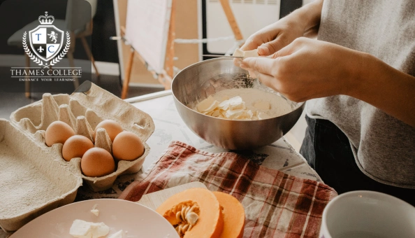 Person preparing dough in a mixing bowl with eggs, flour, and pumpkin on a kitchen counter.