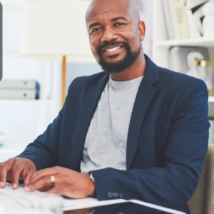 Smiling businessman working on a laptop in a modern office, representing confidence and success in entrepreneurship.