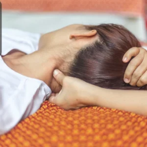 Therapist applying acupressure techniques on a woman’s neck, symbolising relaxation and healing.
