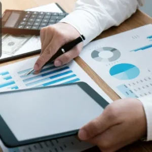 Professional conducting financial analysis using graphs, charts, and a tablet during anti-money laundering and internal audit training.
