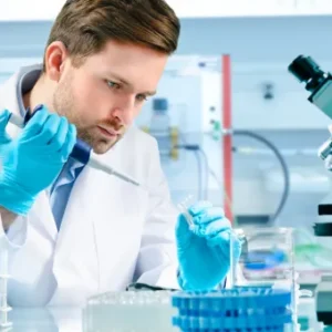 Male laboratory technician in a white coat using a pipette while conducting experiments in a modern science lab.