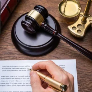 Close-up of a person signing a legal document with a golden pen, next to a judge’s gavel, scales of justice, and a law book, with the Thames College logo in the top left corner.