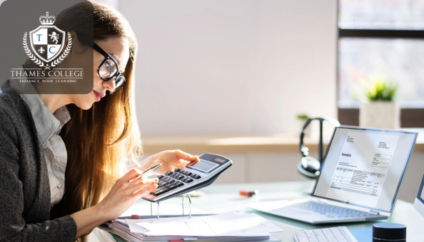 Woman working on a calculator and reviewing invoices on a laptop, symbolising attention to detail in accounts payable.