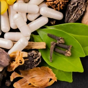Herbal medicine ingredients and capsules on a black background representing natural and alternative medicine practices.